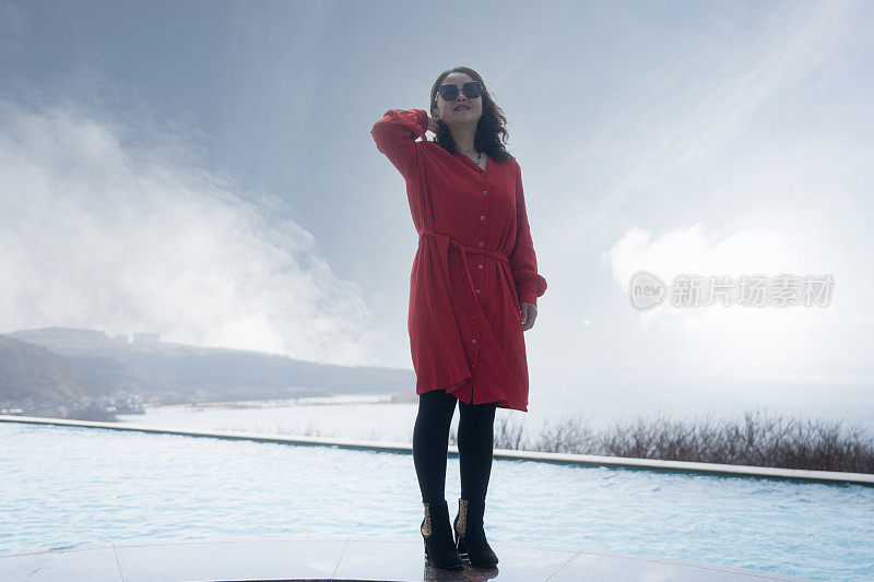 一个穿红衣服的女人坐在泳池边晒太阳