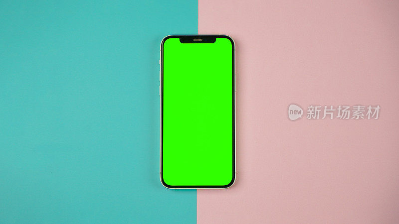手机用空白的绿色屏幕平放，智能手机孤立在蓝色和粉色背景上