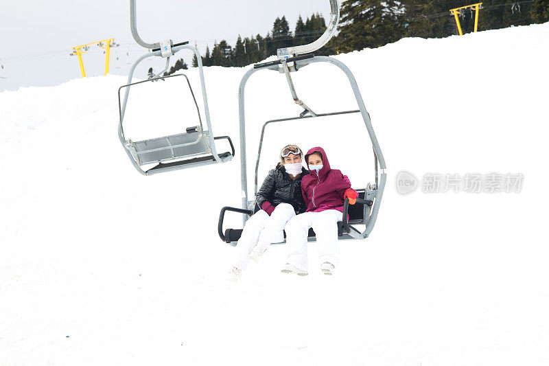 小女孩和她妈妈在滑雪缆车上。