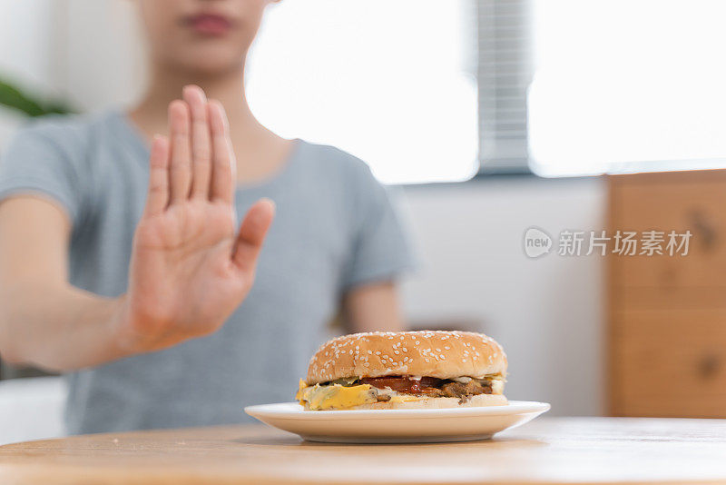 不认识的女人做手势拒绝桌上的汉堡包