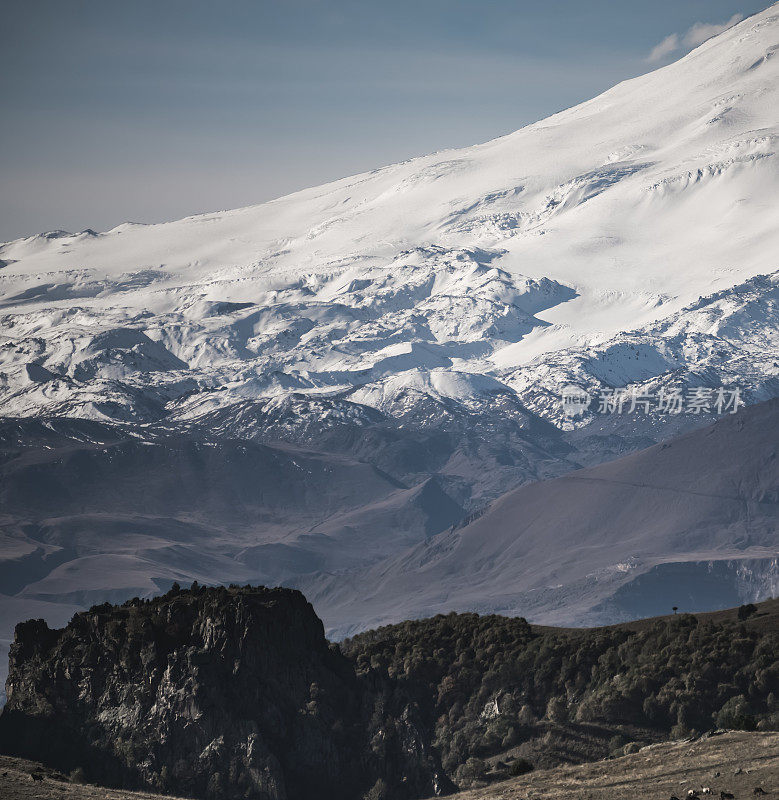 高加索山脉的山坡上有冰川和积雪，靠近有植被的小山，阳光明媚的夏天早晨