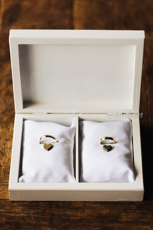 白色盒子里的金婚戒指。柔软的纤维垫。闪亮的珠宝在礼品盒。黄色是爱情的象征。