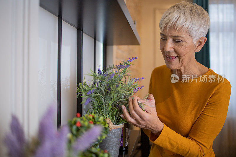 一位年长的妇女在她的新公寓里照料植物