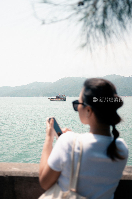 亚洲妇女享受阳光与船在大海的背景