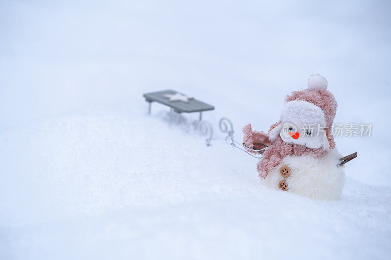 一个小雪人正在雪地上拉雪橇。