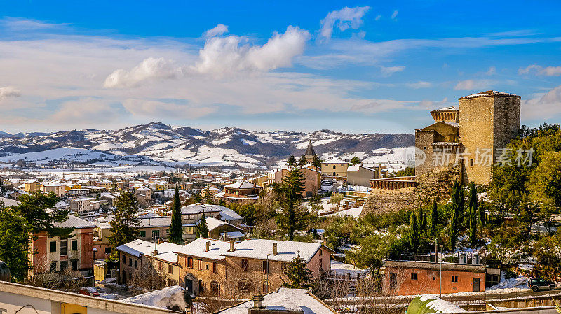 翁布里亚(Umbria)一个中世纪村庄的壮丽冬季风光，位于雪山和森林之间