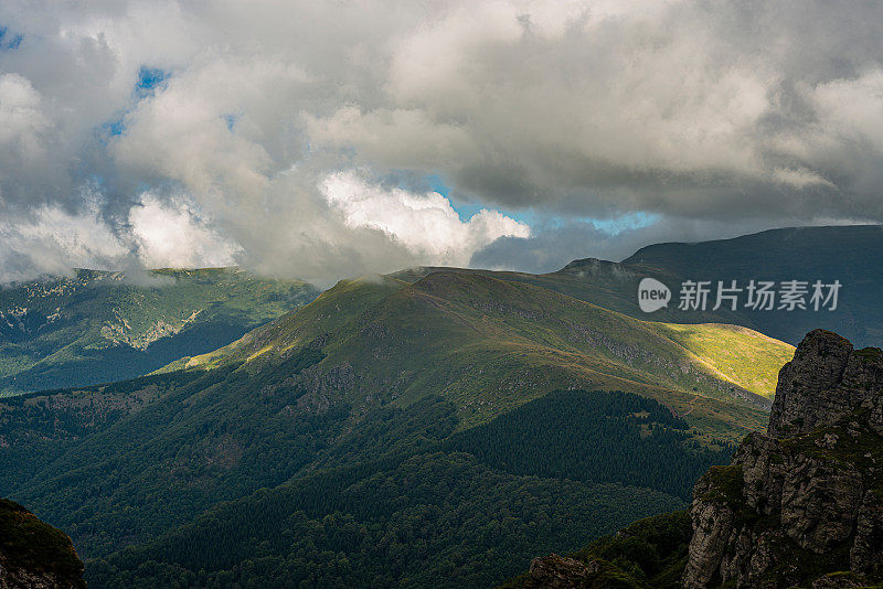 在一个阳光明媚的夏日里，有美丽的山峦和岩石景观。