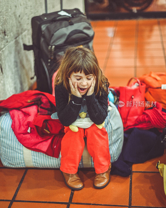 疲惫的年轻女孩在机场带着行李等待家人的旅行延误