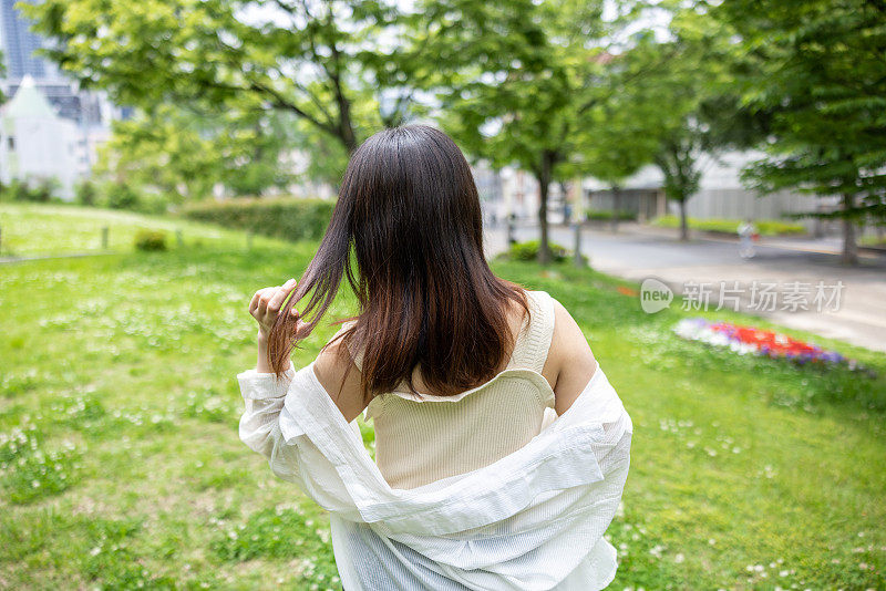 年轻女子在公园散步的后视图