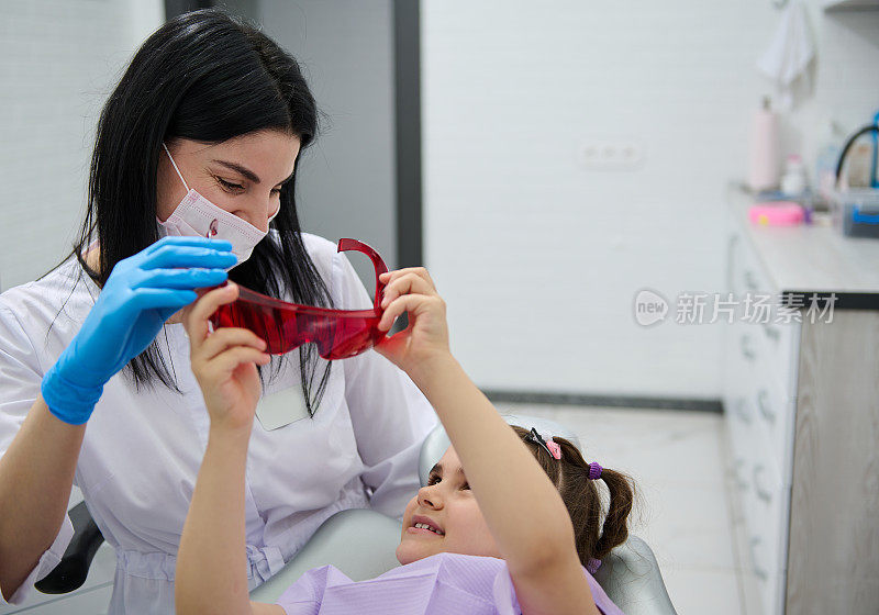 儿科牙医。牙科实践。愉快的女牙医医生在牙科检查前与一个小病人交谈