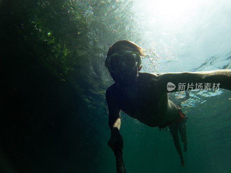 男子在清澈的水中游泳时在水下自拍