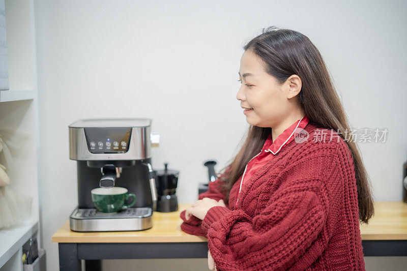 亚洲妇女在家里用咖啡机消耗能量。