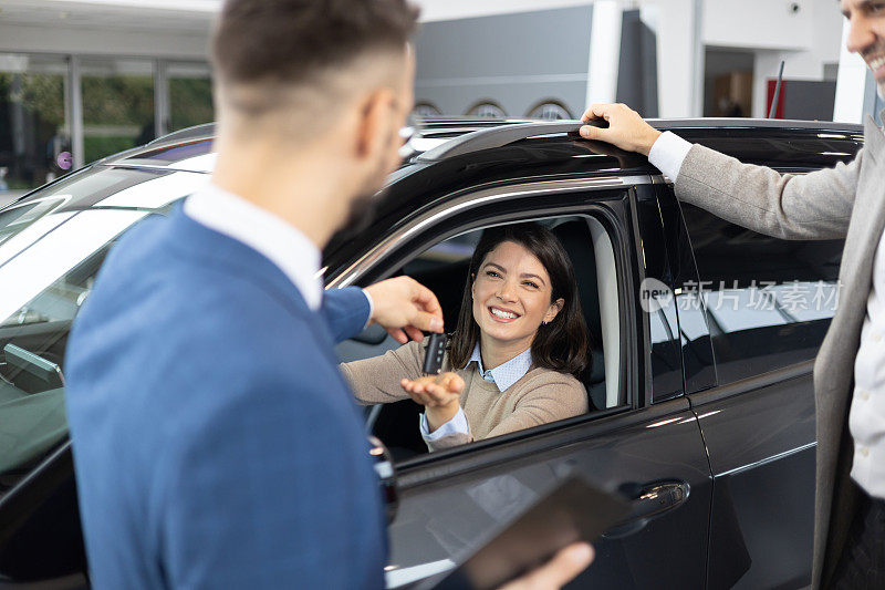 推销员把车钥匙交给汽车经销商的妇女-买方收到新车