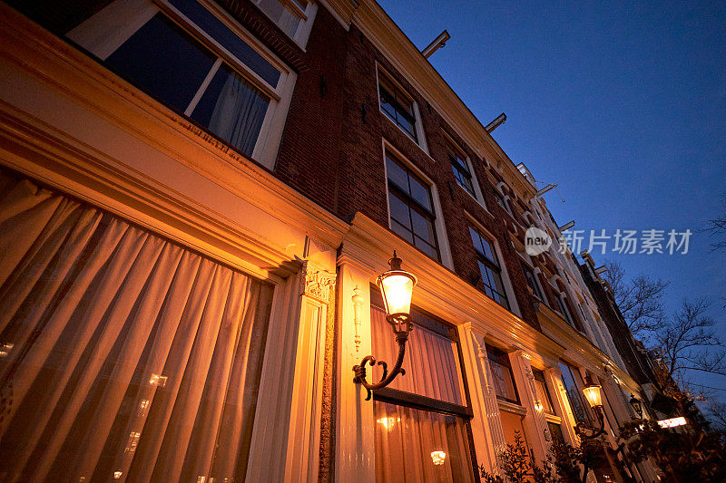 阿姆斯特丹历史悠久的运河房屋立面与夜晚的街灯