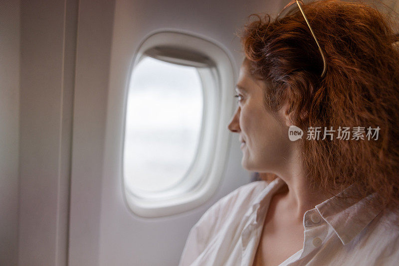 一名白人女子在飞往巴黎的航班上望向窗外