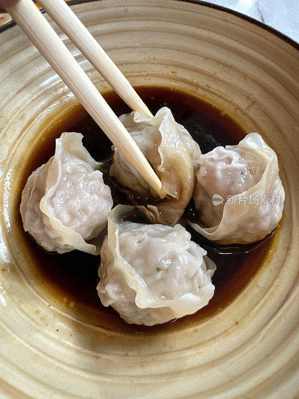 四碗的全画幅图像，蒸Momos(南亚饺子)，白面粉和水面团填充鸡肉和混合蔬菜，酱油蘸酱，不可识别的人用筷子吃饺子，高架视图