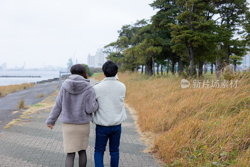 一家人在海滨公园行人路上散步的后景