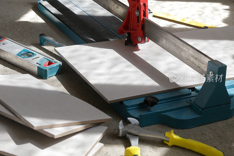 使用标准的手动瓷砖切割机切割瓷砖。瓷砖在浴室中逐步安装的过程。DIY家居装修。