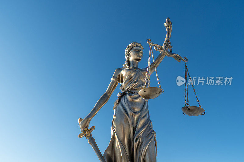 法官雕像与正义的尺度与深蓝色的天空背景