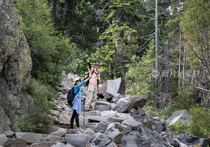 一对夫妇举着登山杖，在鹰湖小径上欣赏风景。翡翠湾。南太浩湖。加州。