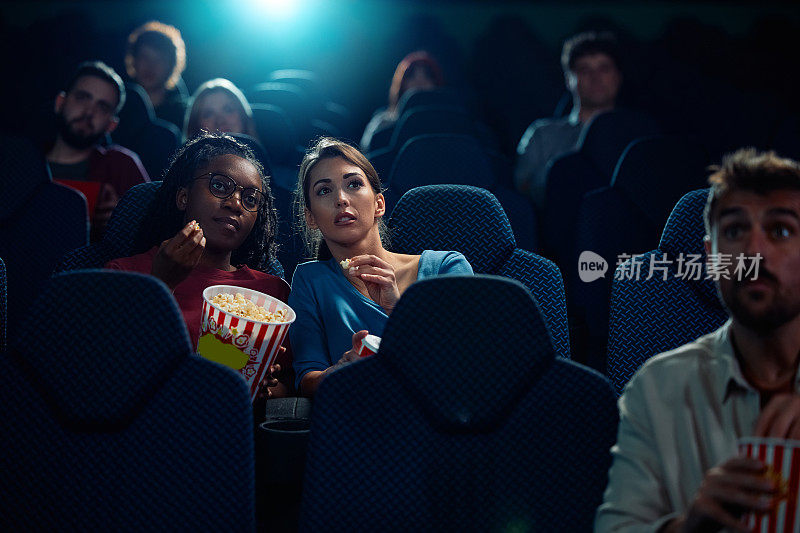 年轻女性在电影院观看悬疑电影。