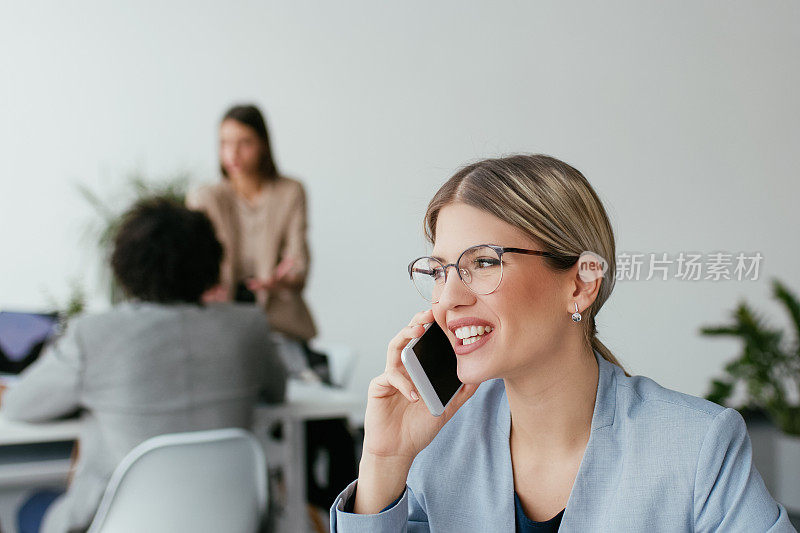 年轻的女商人在办公室里打电话