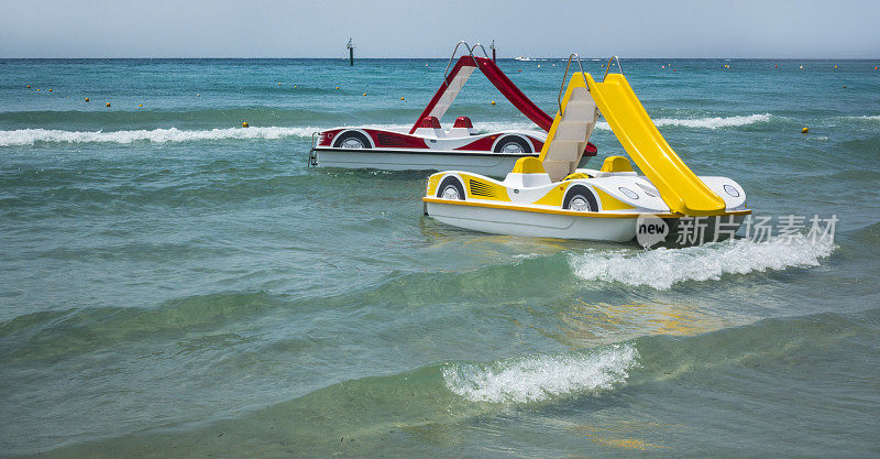 希腊海滩上的两艘带滑水道的脚踏船