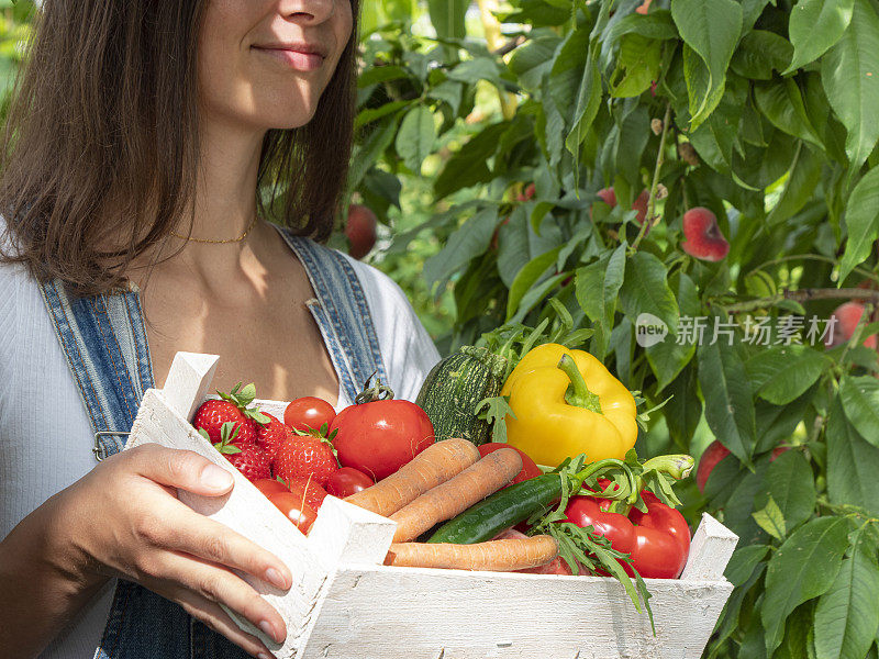 年轻的女加德纳带着满满一箱蔬菜