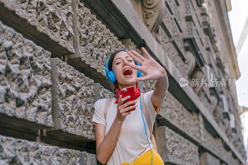 一名年轻女子正带着她的智能手机走在城市的路上