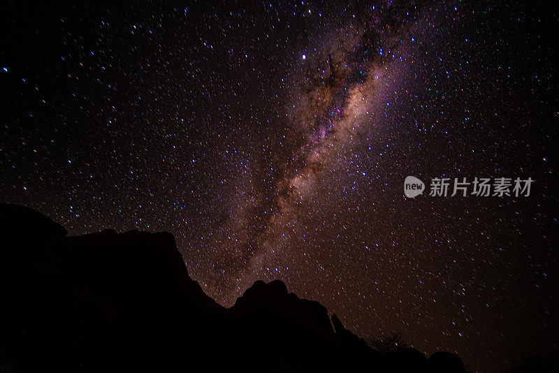 夜晚的星星显示银河系在山的轮廓后面出现