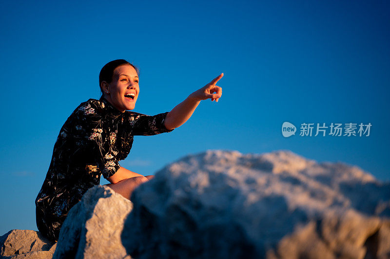 快乐的年轻女子指着户外的复印空间