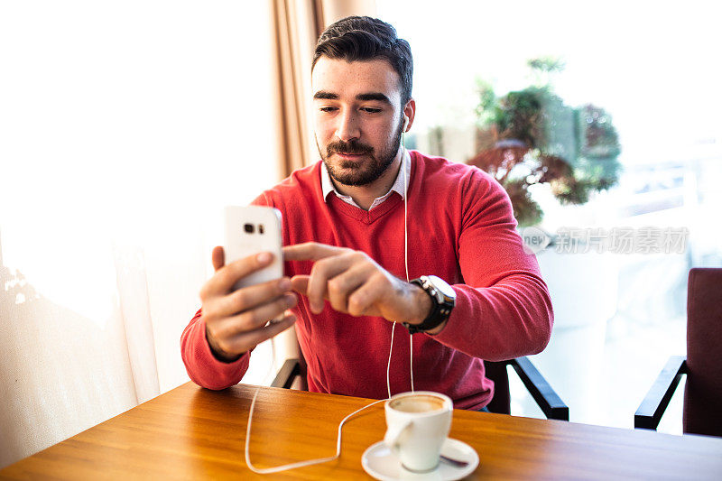 男人坐在café喝咖啡和使用手机