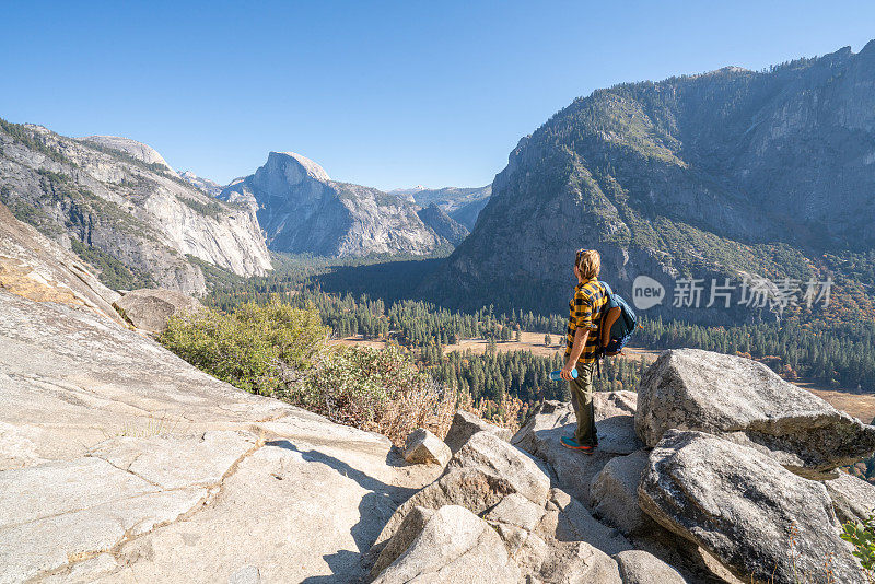 一名徒步旅行者躺在山谷顶上，欣赏着美丽的山景