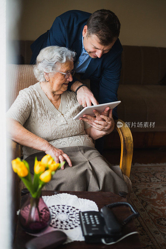 祖母和成年的孙子正在使用数码平板电脑