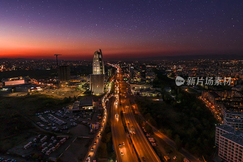 美丽的夜空鸟瞰图宽阔的无人机拍摄的夜间交通在索非亚，保加利亚的金融商业区在黄昏