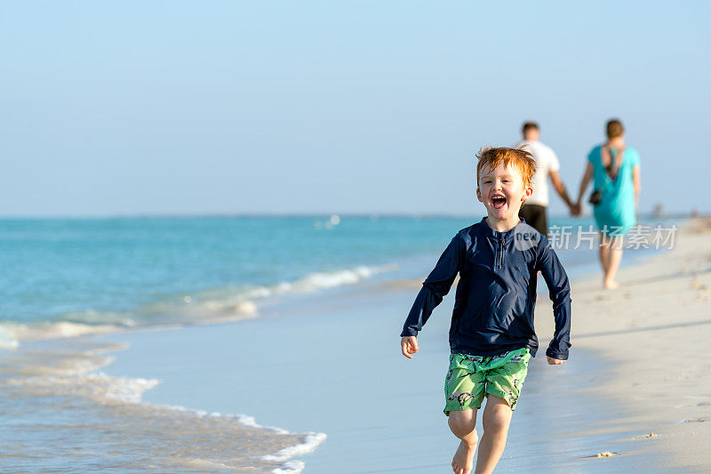 小红发男孩在加勒比海的白色沙滩上奔跑