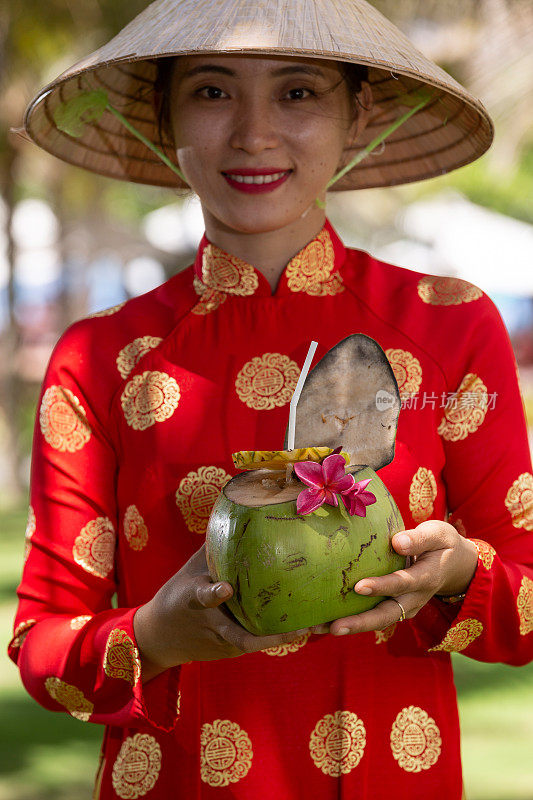 异国情调的传统越南女孩，同时提供新鲜的椰果和鲜花