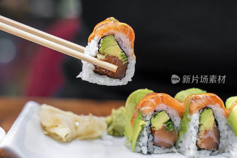 吃寿司武士卷蘸酱油的三文鱼生鱼片