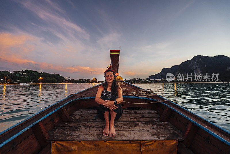 夕阳西下时，在泰国皮皮岛的一艘长尾船上的年轻女子