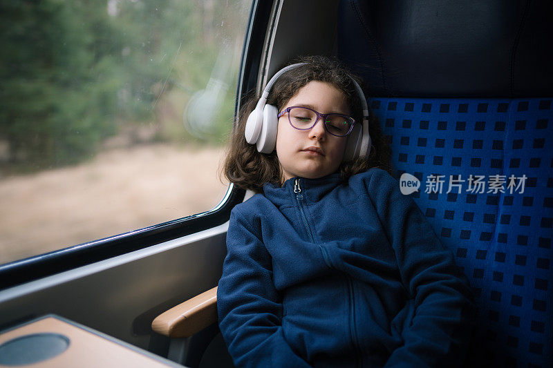 小女孩戴着耳机睡在火车上