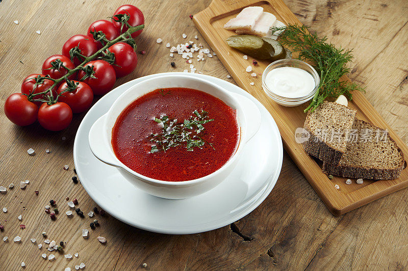 传统的乌克兰菜是木色背景下的白色盘子里的罗宋汤。罗宋汤配培根、黑面包和酸奶油