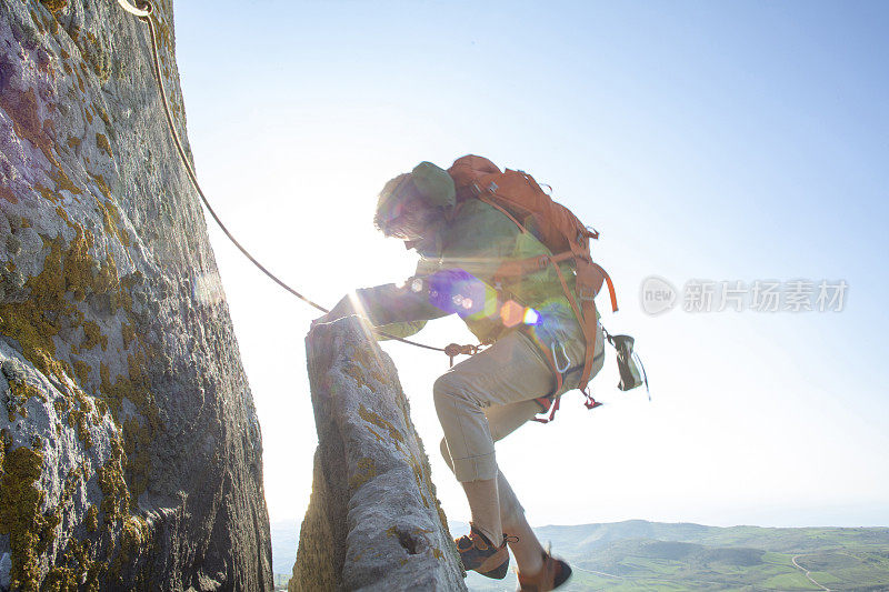 登山者在日出时攀登岩面