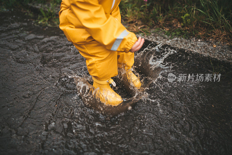 小男孩在雨中玩耍，跳进水里画画