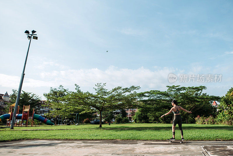 清晨，亚洲华人微笑着在公园玩滑板