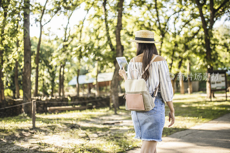 时尚年轻女子放松，使用数字平板电脑和花时间在自然