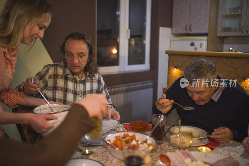 在家里的家庭晚餐上提供食物的年轻女子