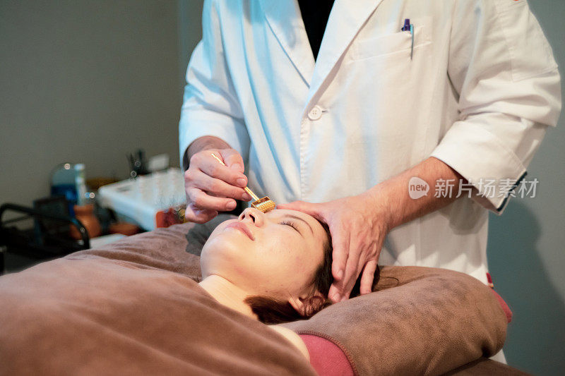 一位针灸专家用针灸针轮按摩脸部皮肤。
