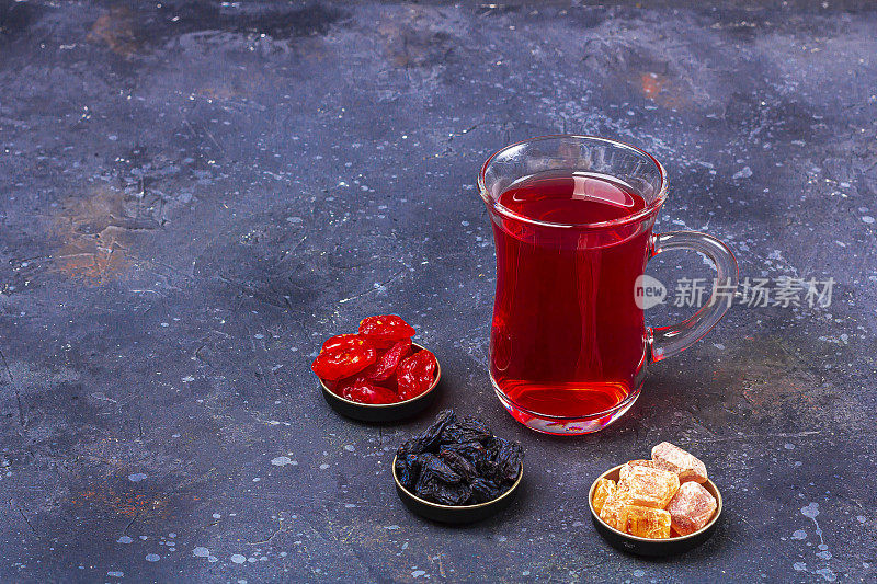 土耳其茶杯(armudu)红茶(roibos，木槿，karkade)和干果(山茱萸，葡萄干)在深色的背景上。草药，维生素，治疗感冒和流感的排毒茶。文本复制空间