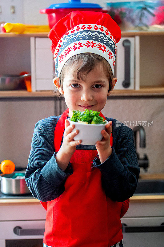 微笑的小男孩站在厨房里展示他的作品