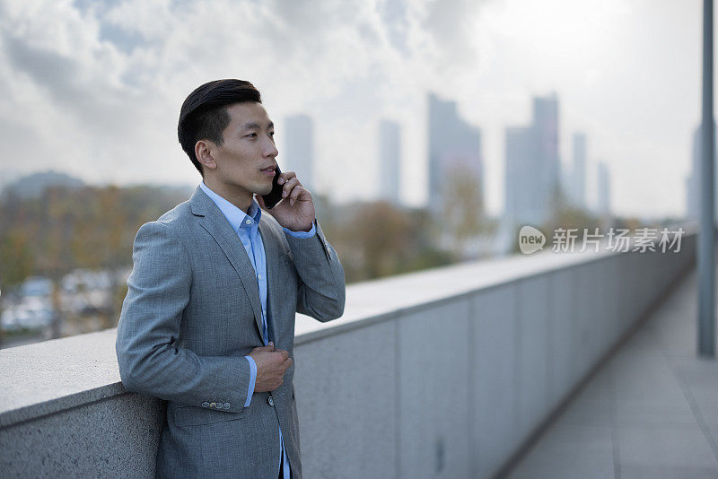 年轻的中国商人在户外使用手机